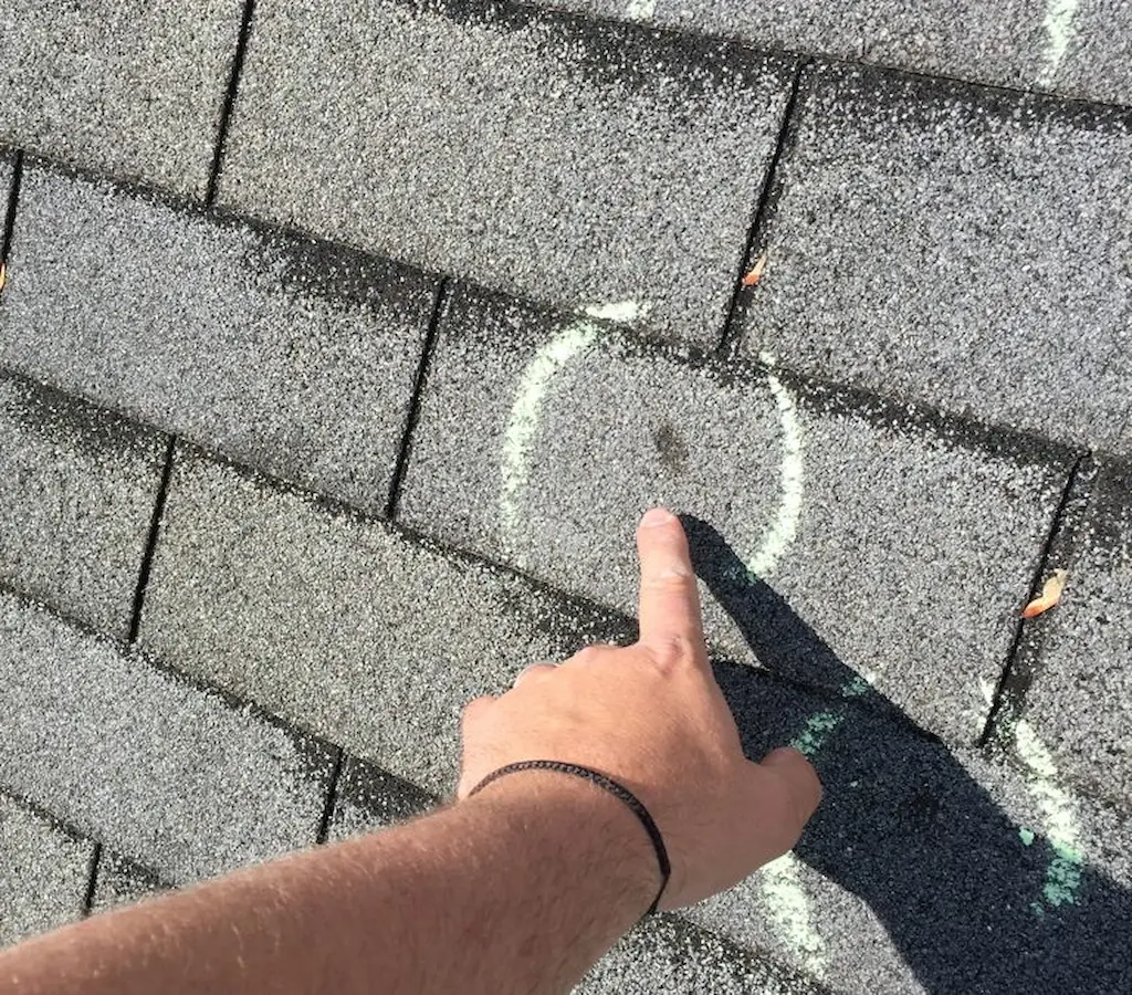 Homeowner taking photos of roof with missing shingles