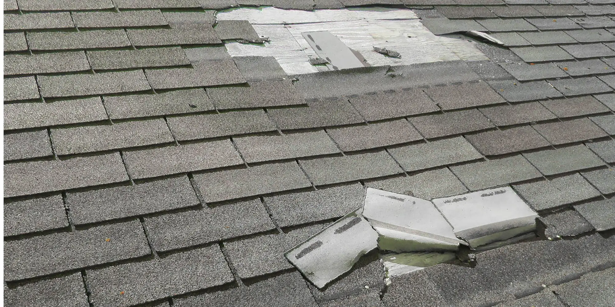 Roof with missing shingles caused by wind storm