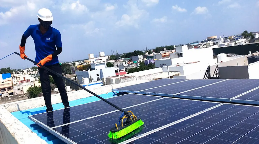 Person cleaning rooftop solar panels, demonstrating easy maintenance.